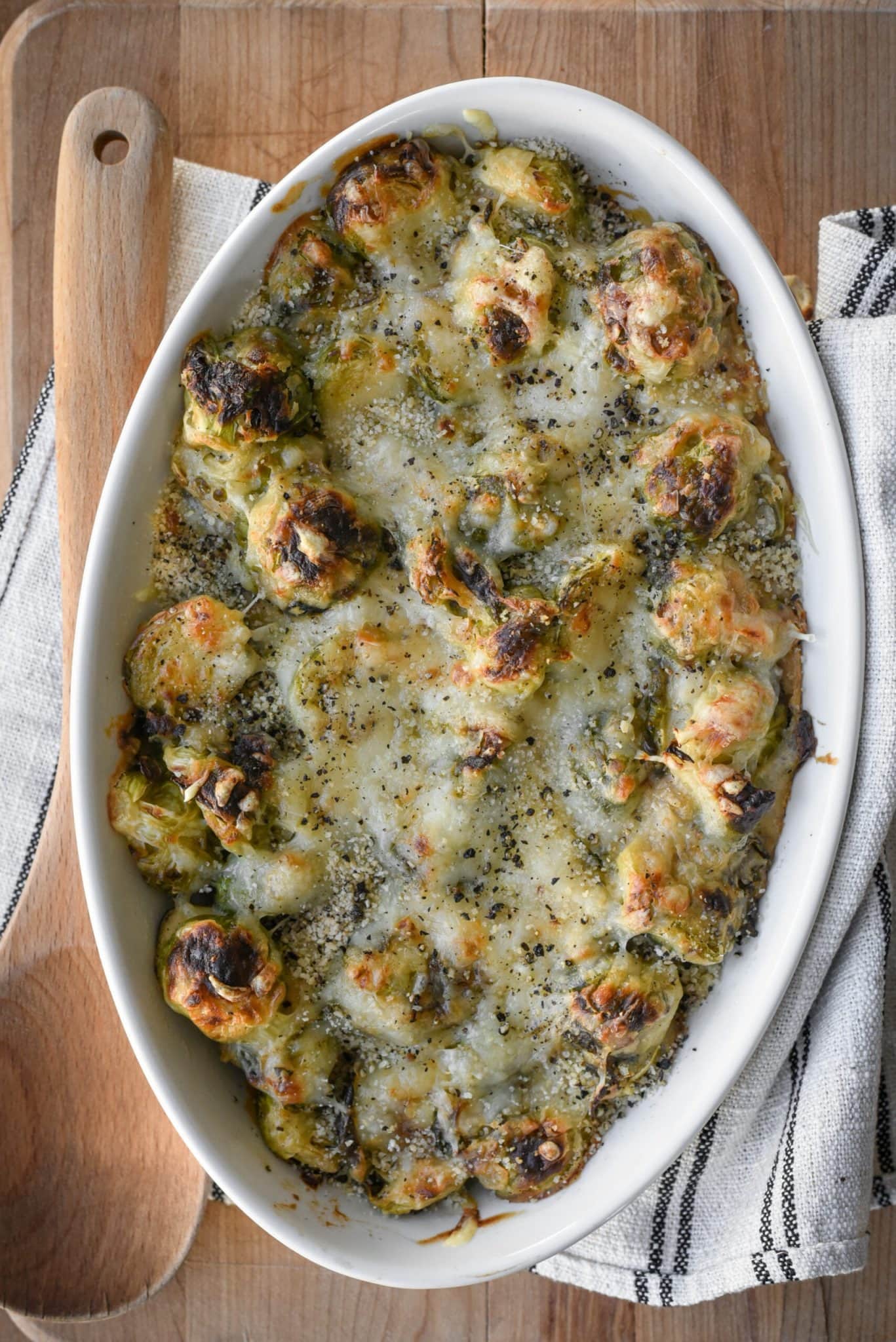 Top view of brussels sprouts baked with creamy sauce on a baking dish. 