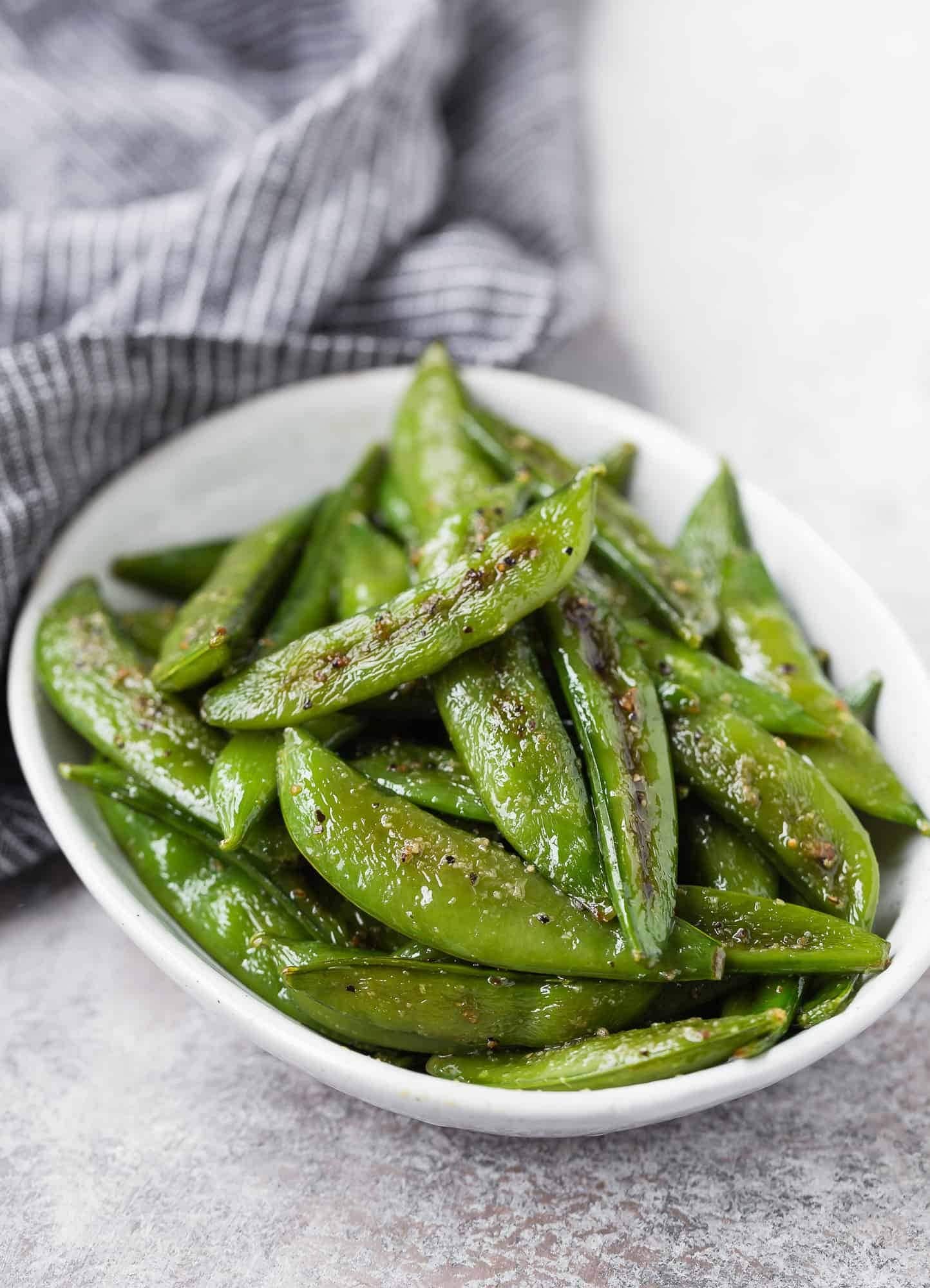 A serving of roasted sugar snap peas on a small bowl. 