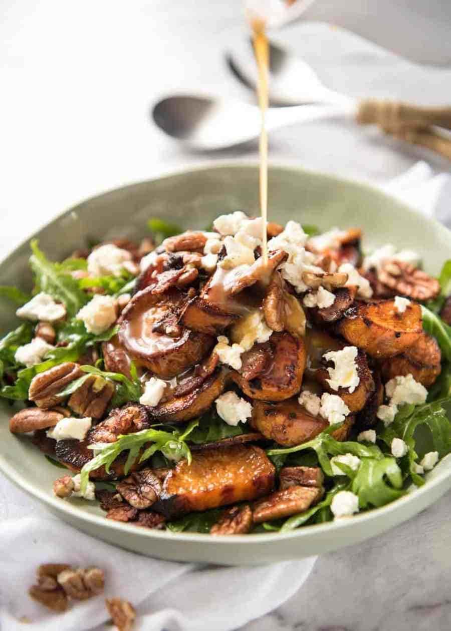 Plate of Roasted Sweet Potato Salad with arugula, goats cheese, pecans and drizzle of Honey Lemon Dressing