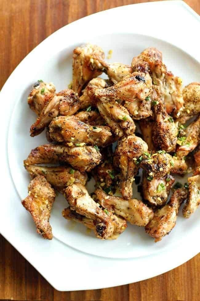 Chicken wings seasoned with pepper and herbs on a white dish plate. 