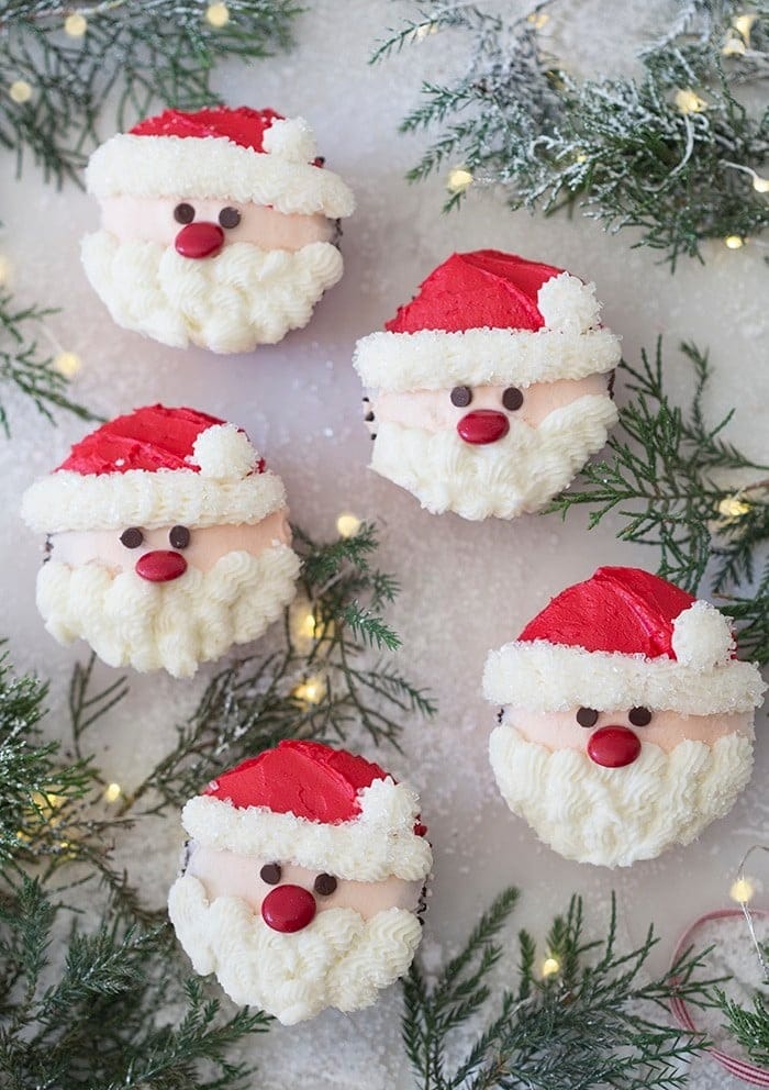 Bunch of cupcakes designed with Santa face using red and white icing.