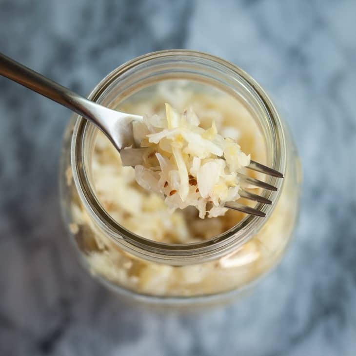 Sauerkraut scooped with a fork from a glass jar. 