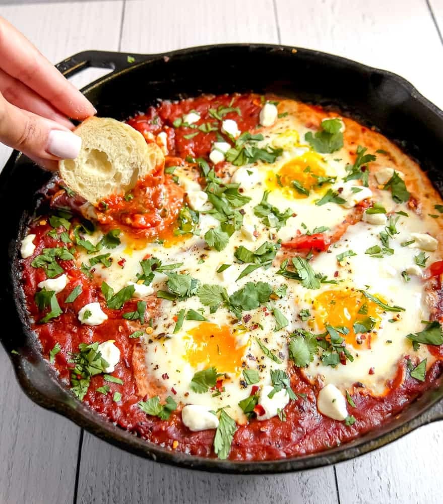 Skillet filled with sautéd bell peppers, onions, with eggs poached in a flavorful tomato sauce with spices and aromatics