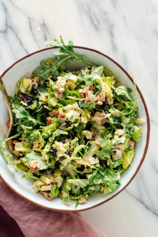 Salad on a bowl with shredded sprouts, arugula, pecans, and cherries