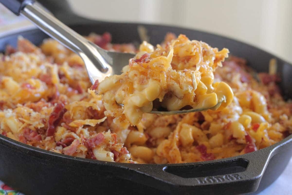 Elbow pasta with bacon and cheese toppings on a cast iron