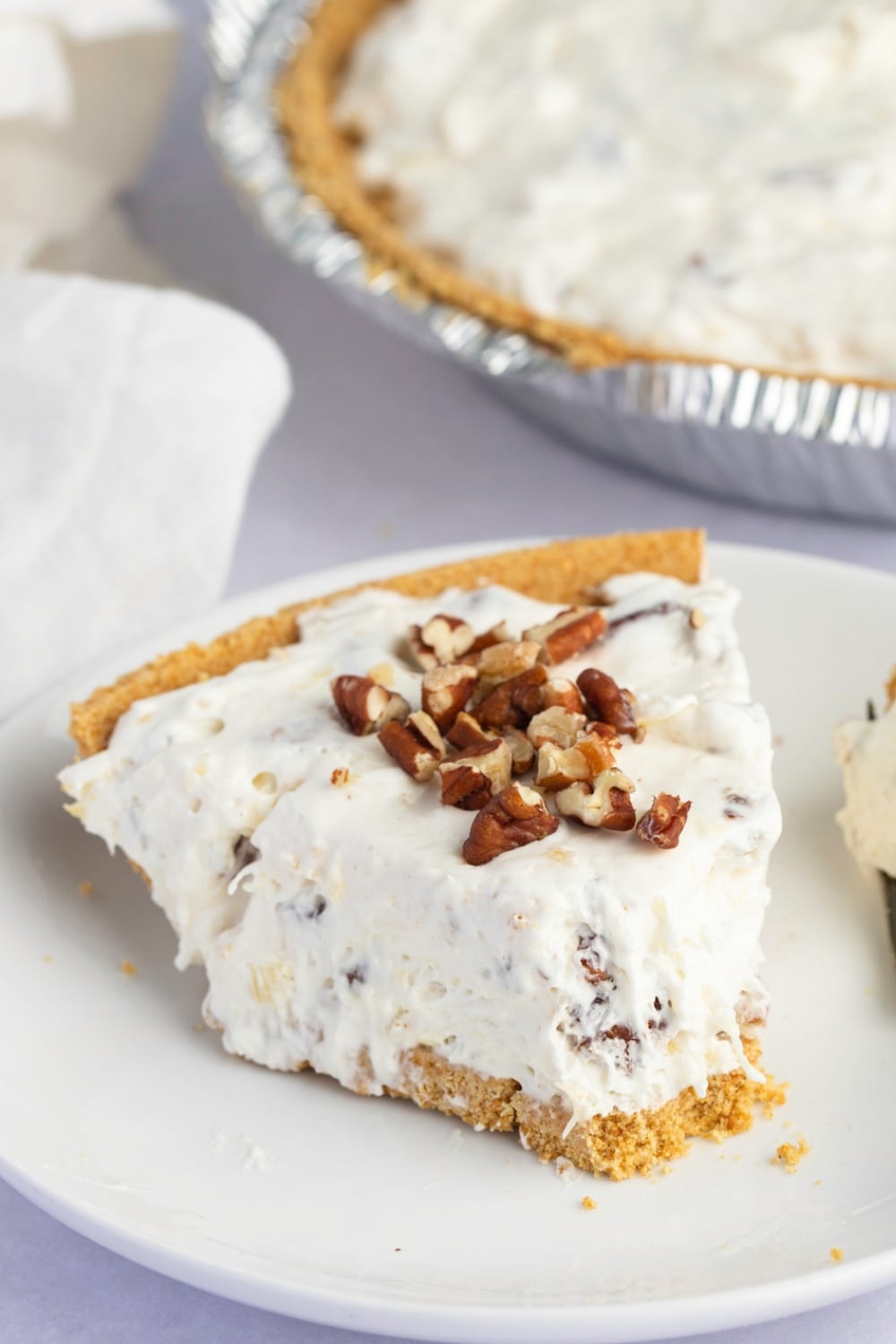 Millionaire pie slice topped with chopped pecans served on a white plate.