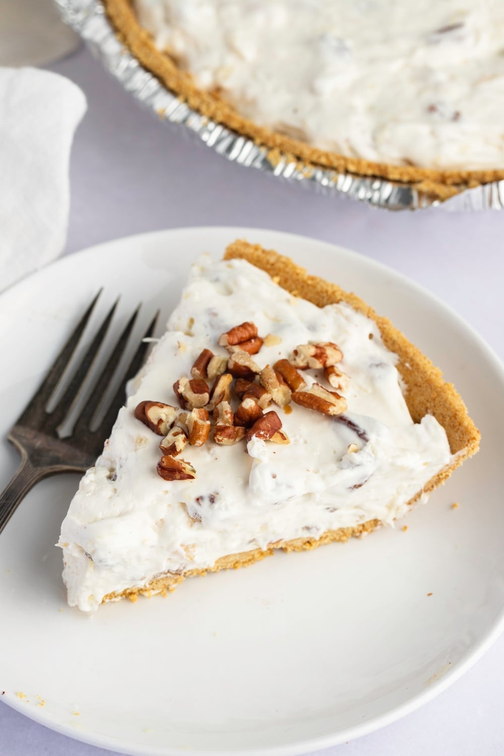 A slice of creamy millionaire pie with chopped pecans on top.
