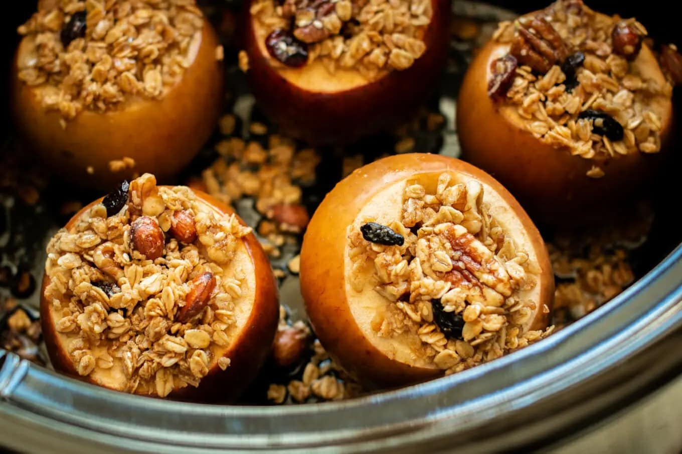 Baked apples with granola, melted butter, and maple syrup on a slow cooker.