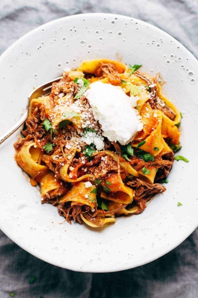 Beef Ragu with pappardelle pasta and garnished with parmesan, ricotta, and parsley for topping