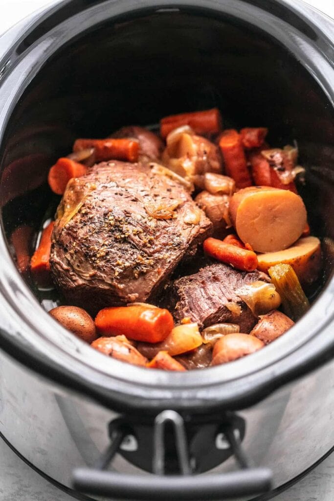 Roast beef in slow cooker with seasoned baby potatoes and carrots. 