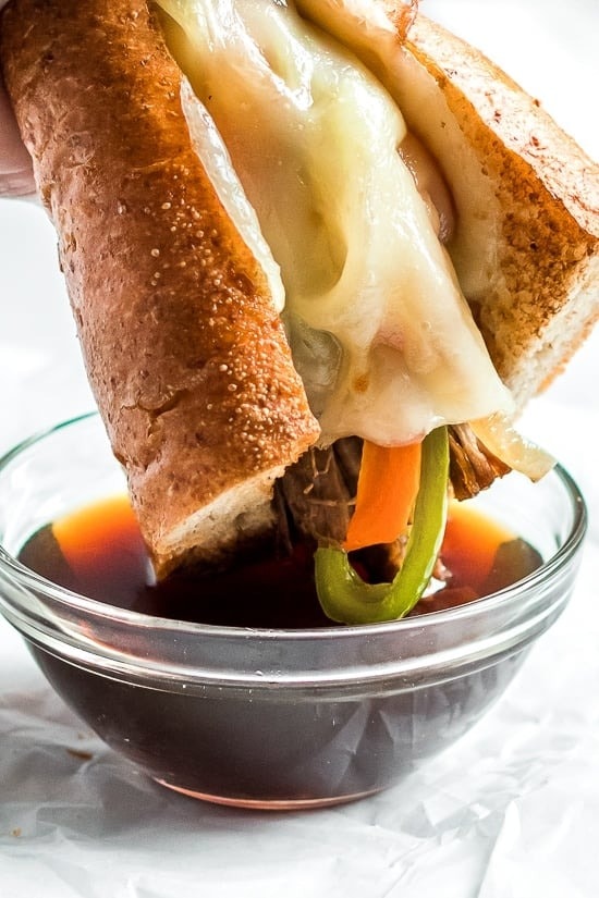 French Dip Sandwich filled with beef, melted cheese, caramelized onions and a beef broth to dip
