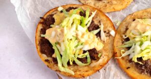 Thin and crispy smash burger taco topped with ground round patty, lettuce, onions and mayo