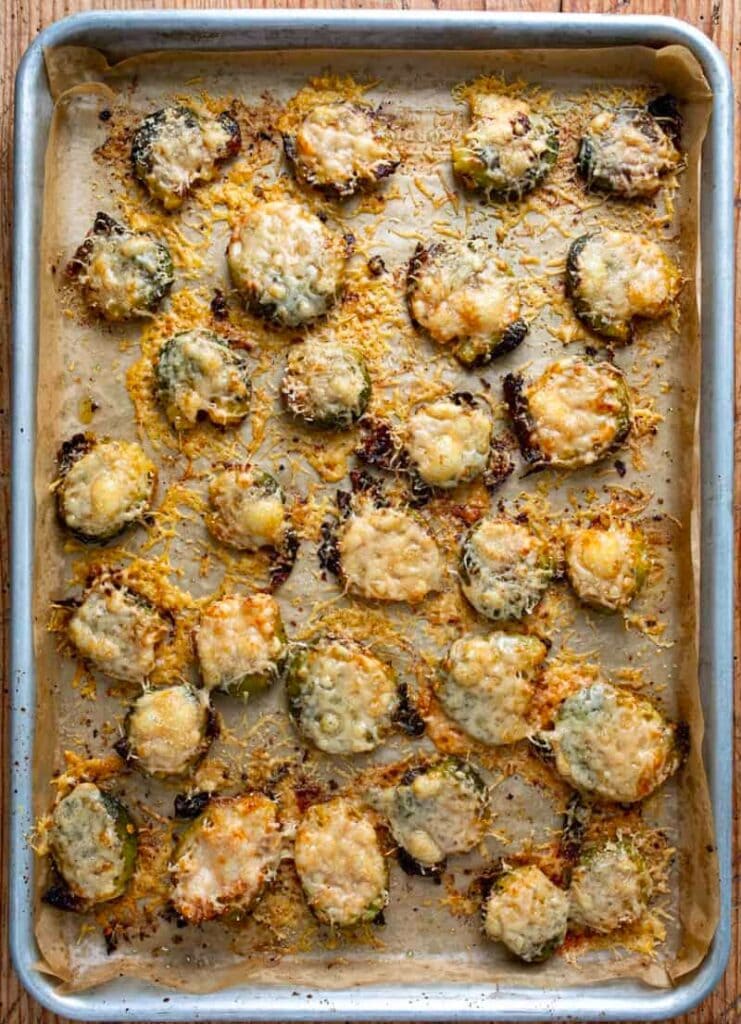Baked smashed brussels topped with cheese on a sheet pan.