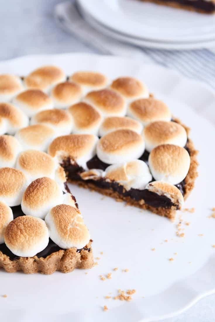 Smores chocolate pie on a cake plate with a slice missing.