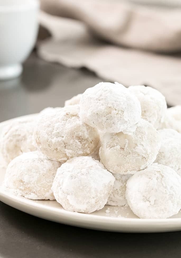 Snowball cookies covered in powdered sugar on a plate.
