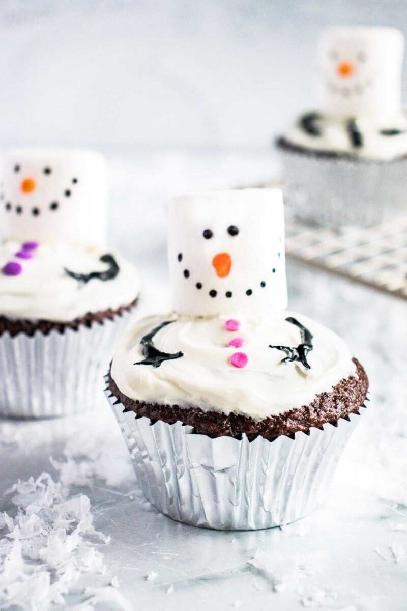 Chocolate cupcakes topped with frosting and marshmallows decorated as snowman. 