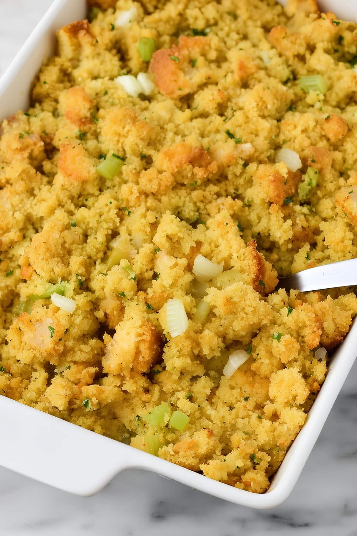 Homemade cornbread dressing in a white baking dish. - 4
