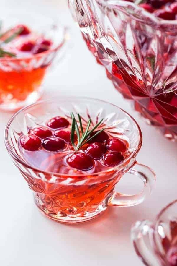 Cranberry drink in a glass bowl and mug, garnished with rosemary sprigs