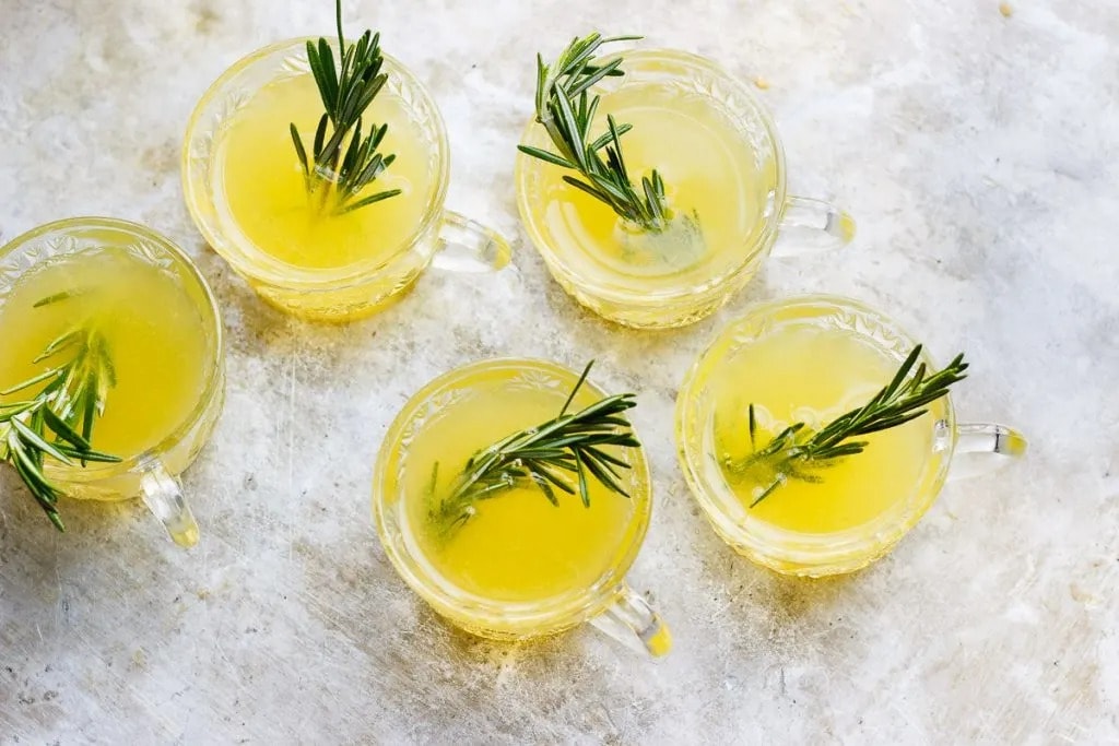 Top view of glasses filled with sparkling winter punch garnished with fresh rosemary leaves.