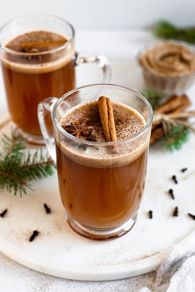 Spiced rum served on a glass mug garnished with cinnamon powder and stick.