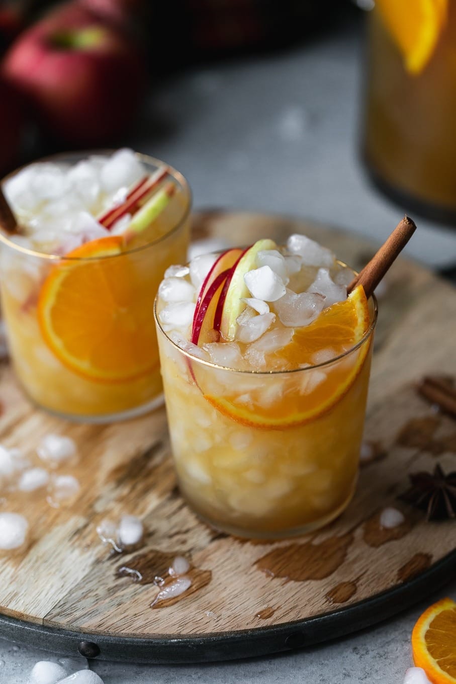 Spiced orange apple cider sangria in glasses topped with whipped cream and cinnamon sticks.