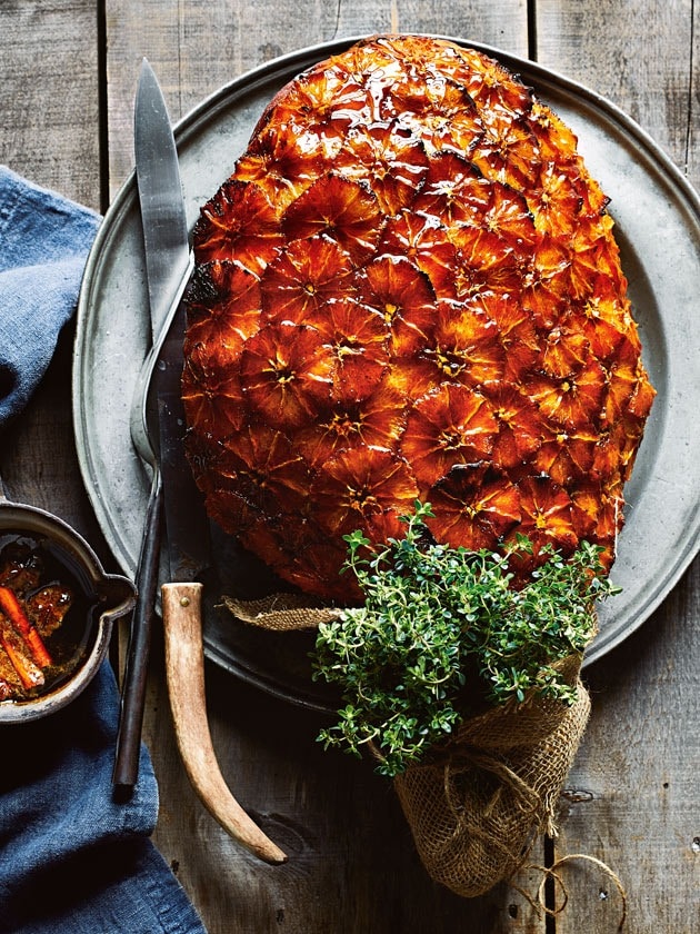 Spiced pomegranate and glazed ham served on a round pan with fork and knife. 