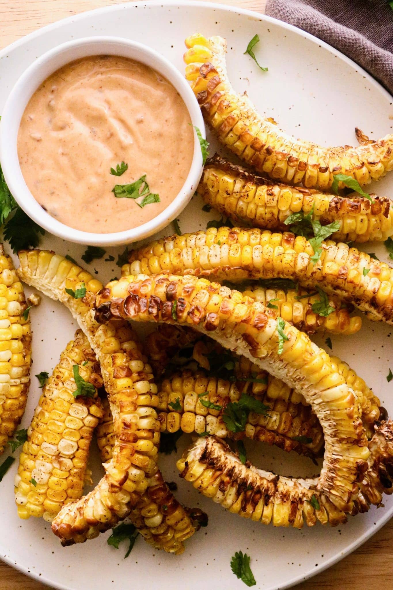 Seasoned corn ribs served with Chipotle dip on a plate.