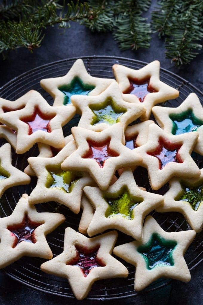 Bunch of star shaped cookie cutters on a cooling rack with colorful glass candies in the middle. 