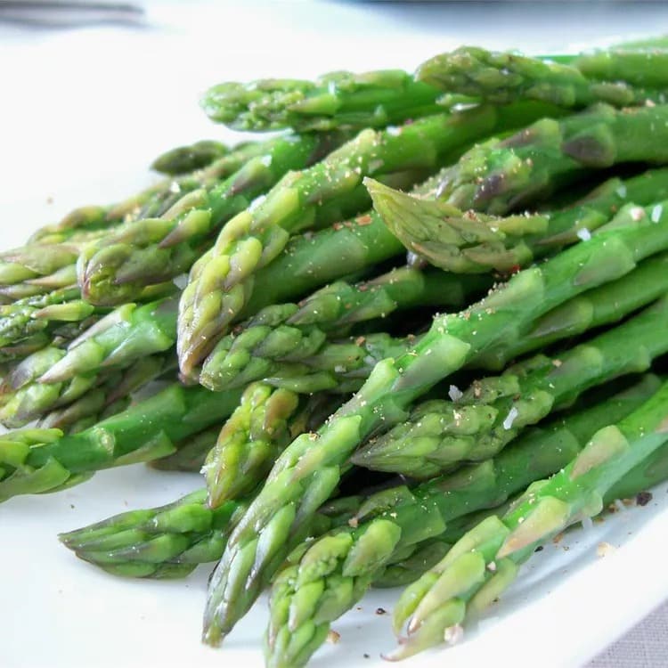 Bunch of steamed asparagus served on a white plate. 