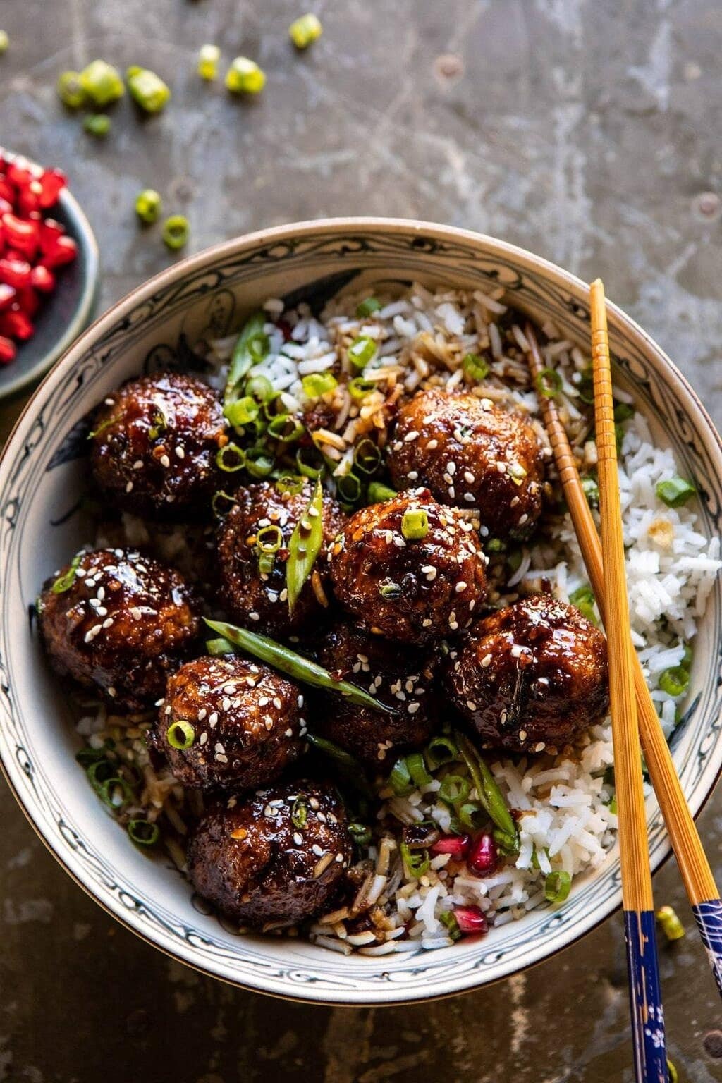 Rice topped with saucy meatballs sprinkled with sesame seeds and chopped chives. 