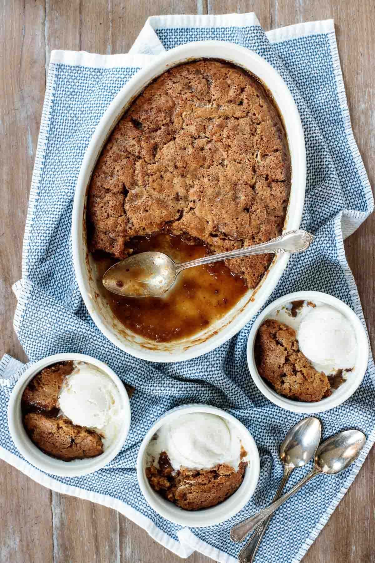Toffee pudding in a casserole served on small mugs with scoop of vanilla ice cream. 