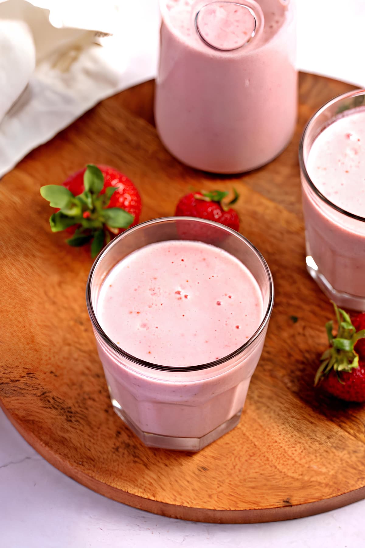 Fresh strawberries beside strawberry milk served on glasses. 