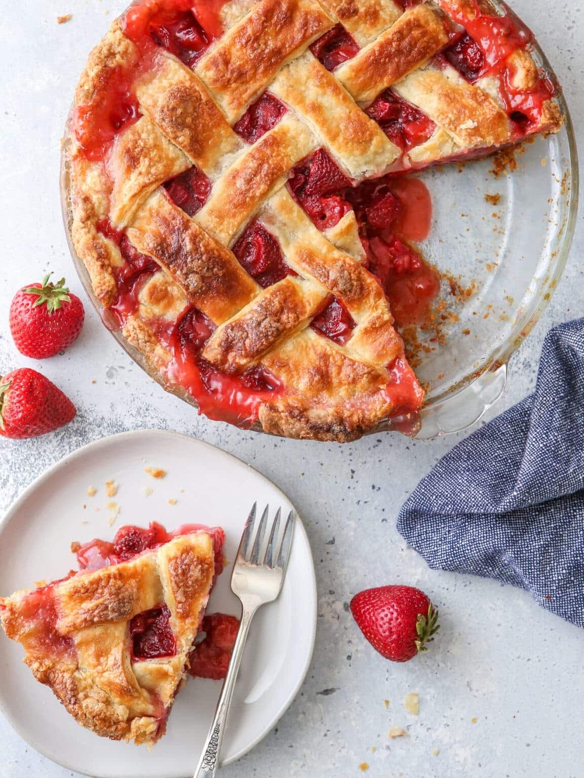 A strawberry pie with a beautifully woven lattice crust sliced, served on a plate.