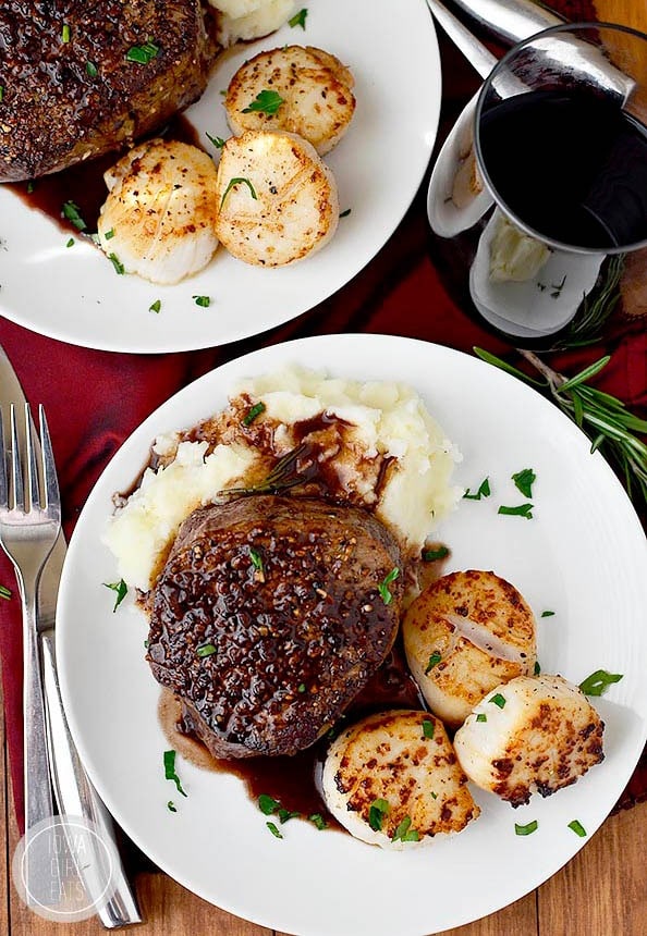 Two plate servings of  filet mignon topped on mashed potatoes and silky scallops.