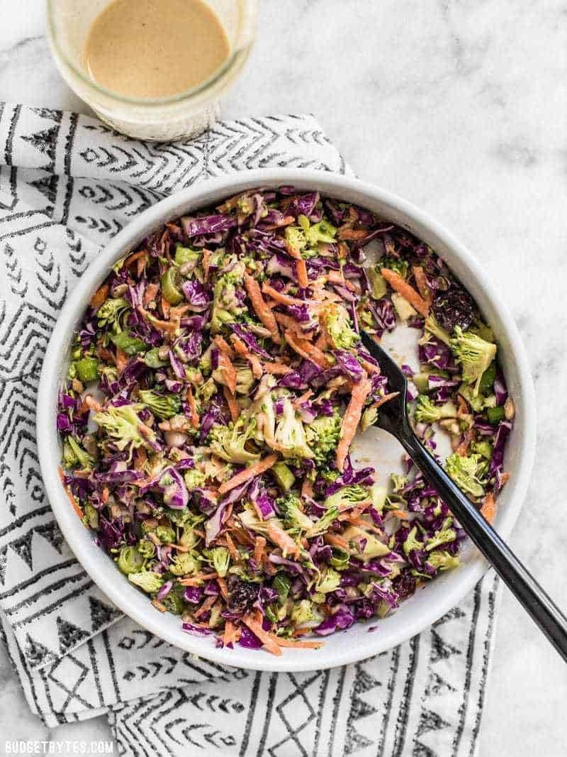 Bowl of winter salad with broccoli, cabbage, carrots, onions, and a maple tahini dressing