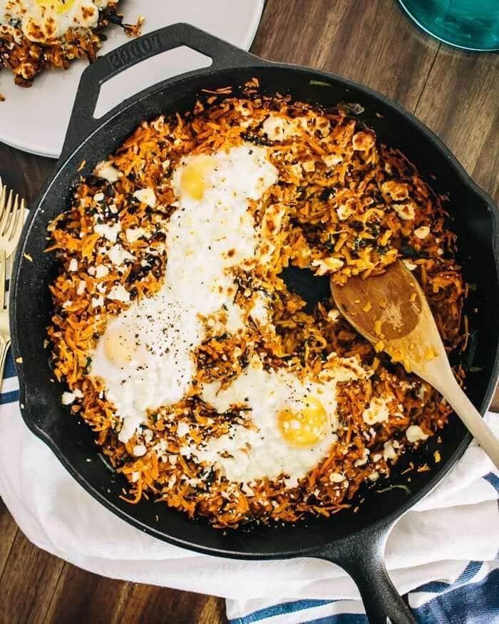 Crispy shredded sweet potatoes, leafy greens, eggs and feta cheese cooked in a skillet.
