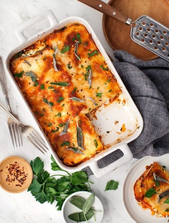 Sweet potato lasagna on a casserole dish with  herbs, cheese, and marinara sauce.