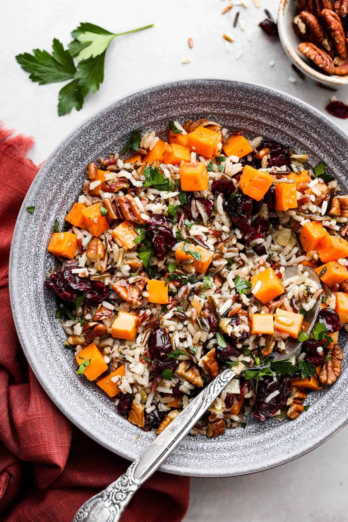 Rice pilaf on a bowl with tender sweet potatoes, pecans, and cranberries.