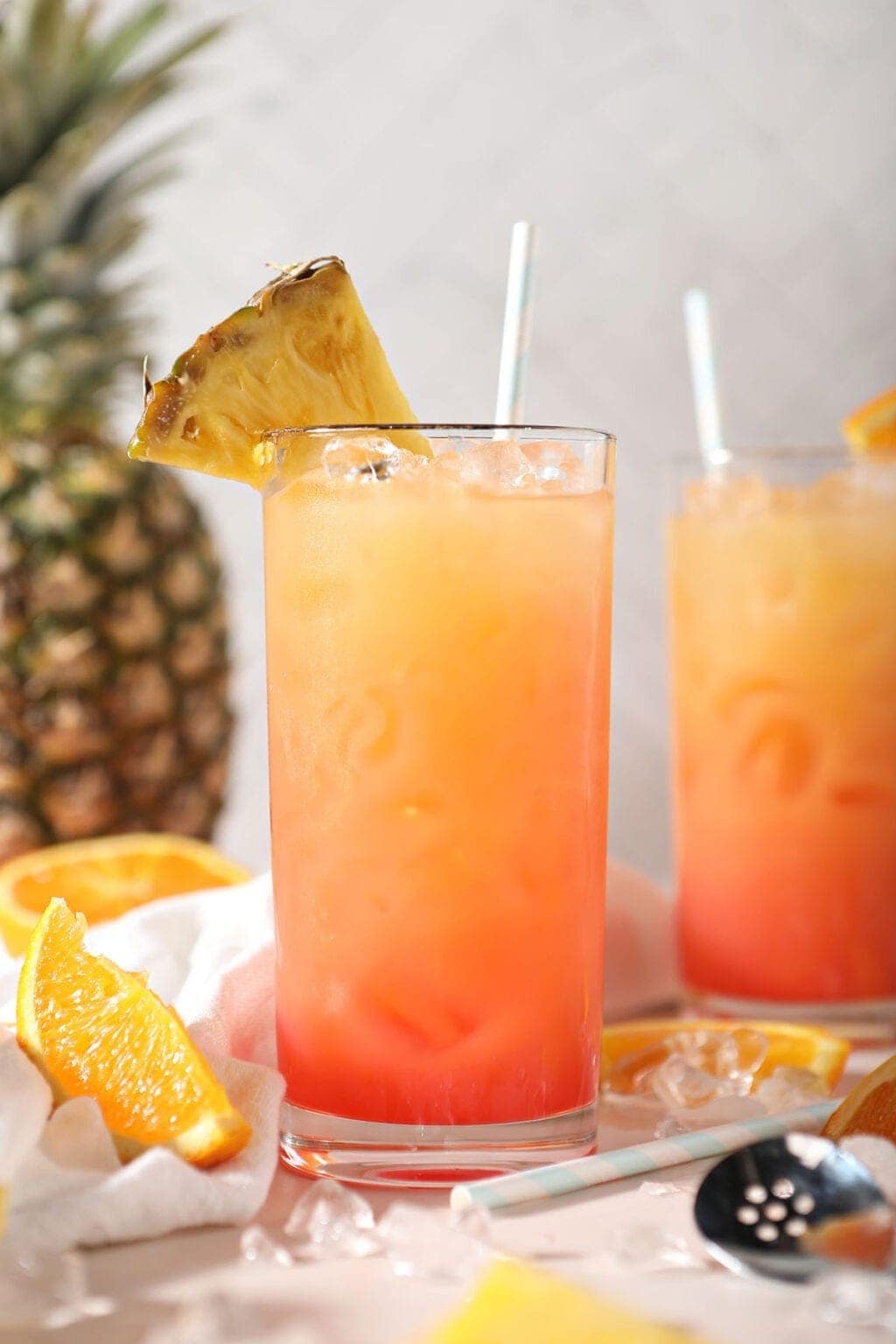 Two glasses of refreshing orange and pineapple juice with a slice of pineapple on top.