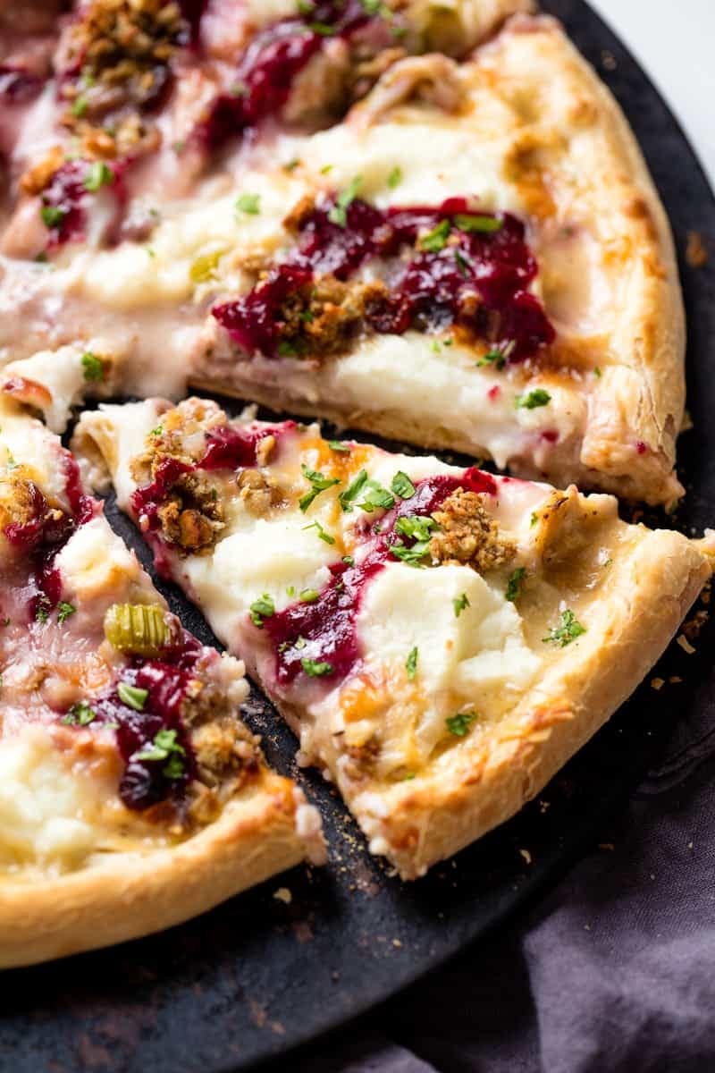 Sliced pizza with melted cheese, cranberry sauce and nuts toppings. 