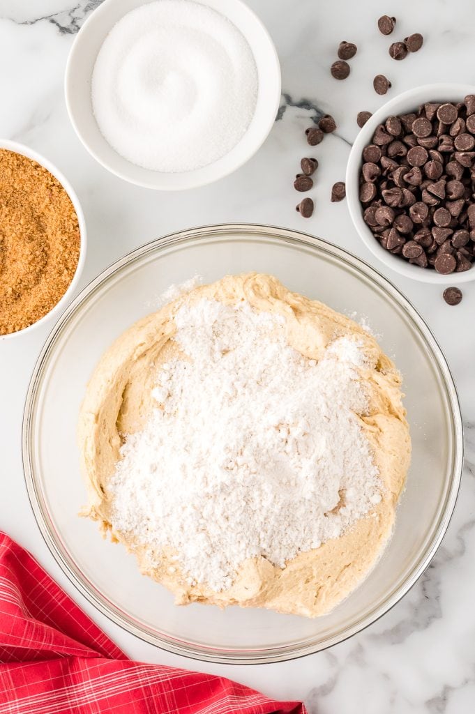 A mixture of dry baking ingredients over creamed butter in a glass bowl.