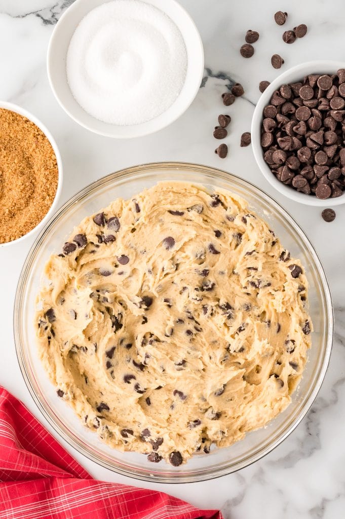Chocolate chip cookie batter in a glass bowl.
