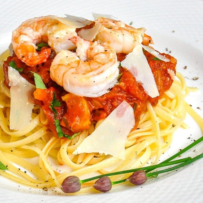 Pasta topped with tomato fennel sauce garnished with shrimp. 
