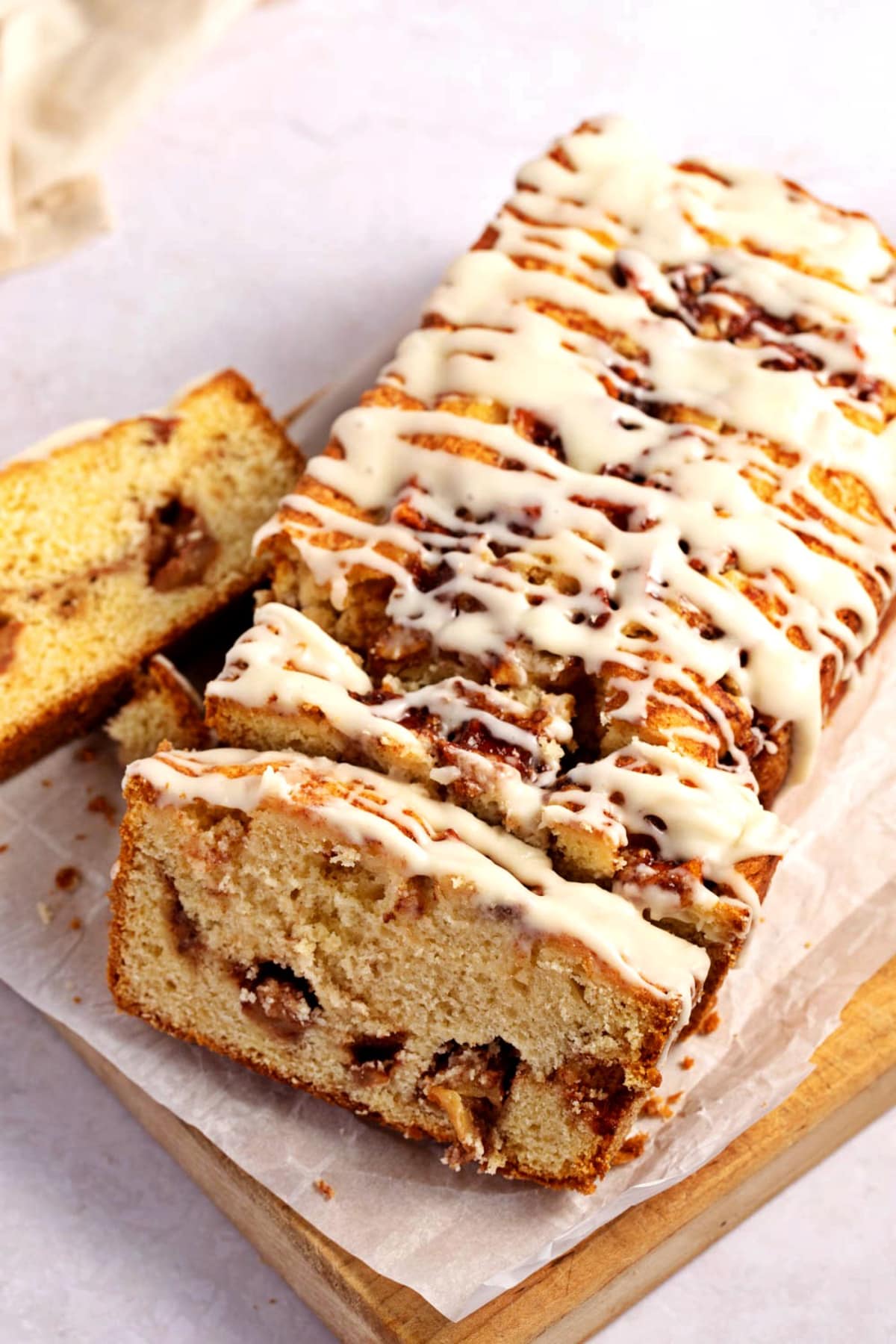 Top view of slices of apple bread fritter loaf bread with drizzle of white sugar glaze on top. 