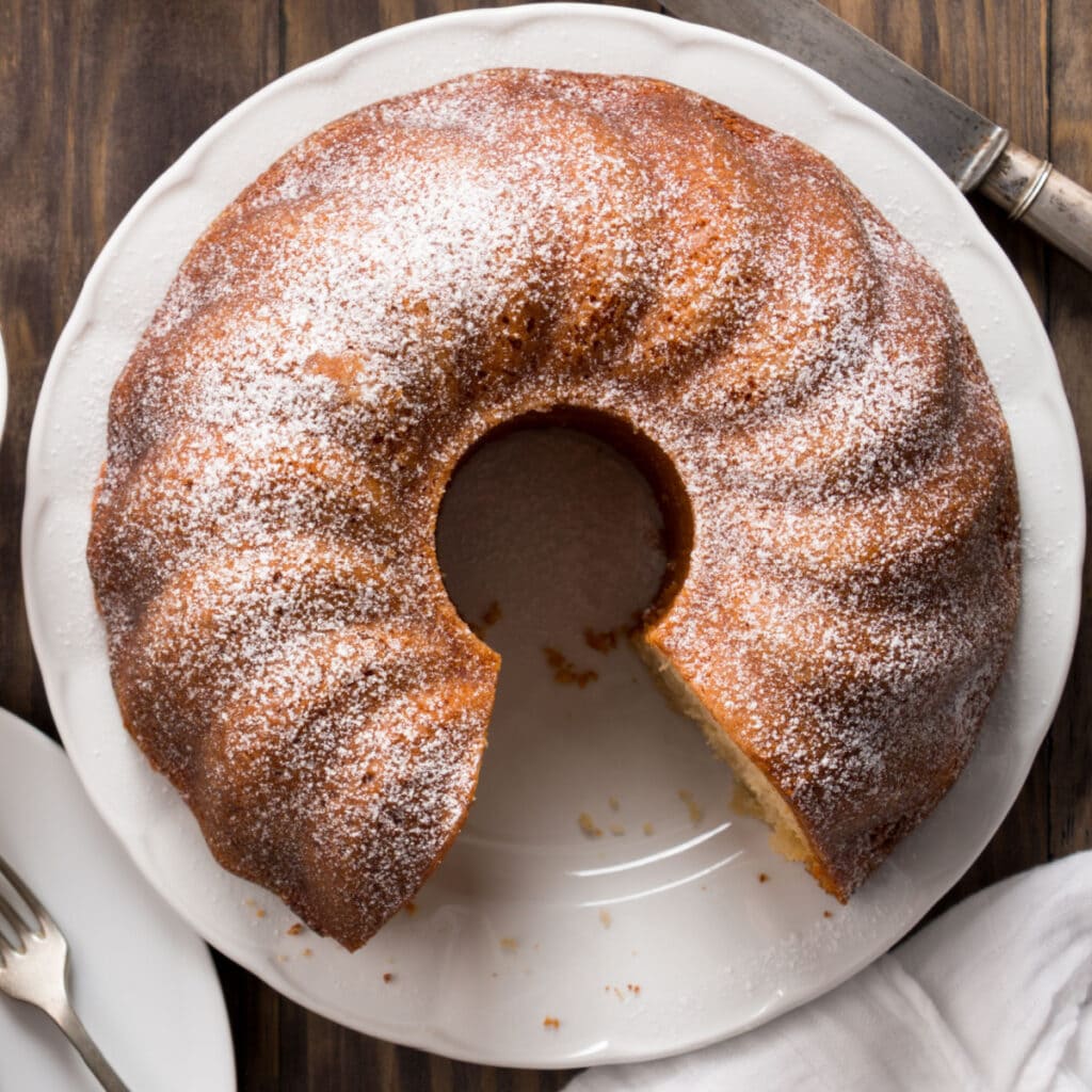 Crack cake with a slice missing with sugar glaze on a plate. 