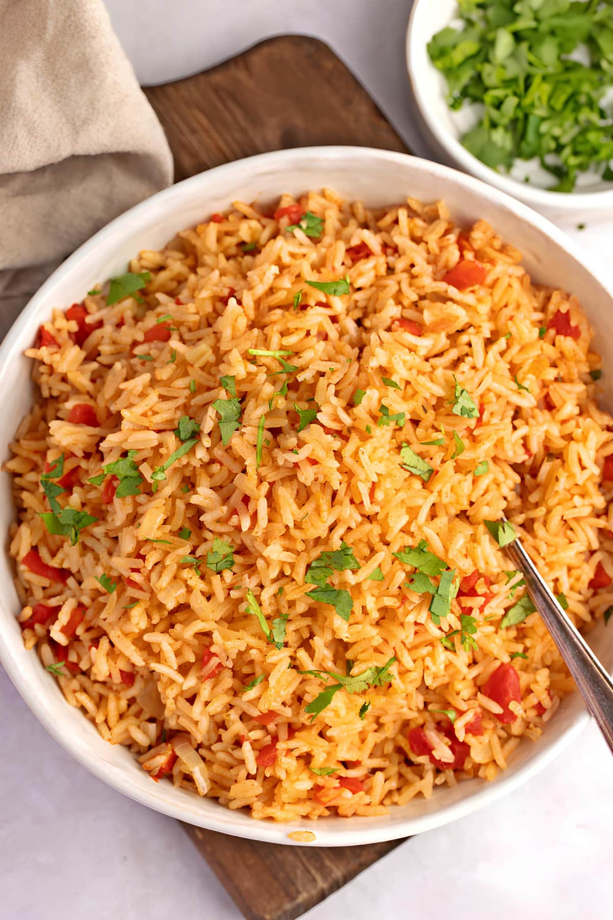 A bowl of Spanish rice with parsley leaves garnish.