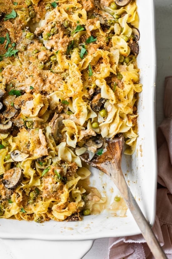 Tuna noodle casserole with mushrooms, peas, noodles in creamy sauce served on a white dish.  