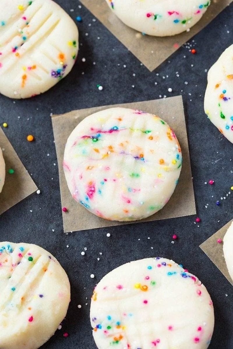Cookie dough cookies with rainbow candies flat lay on a parchment paper.