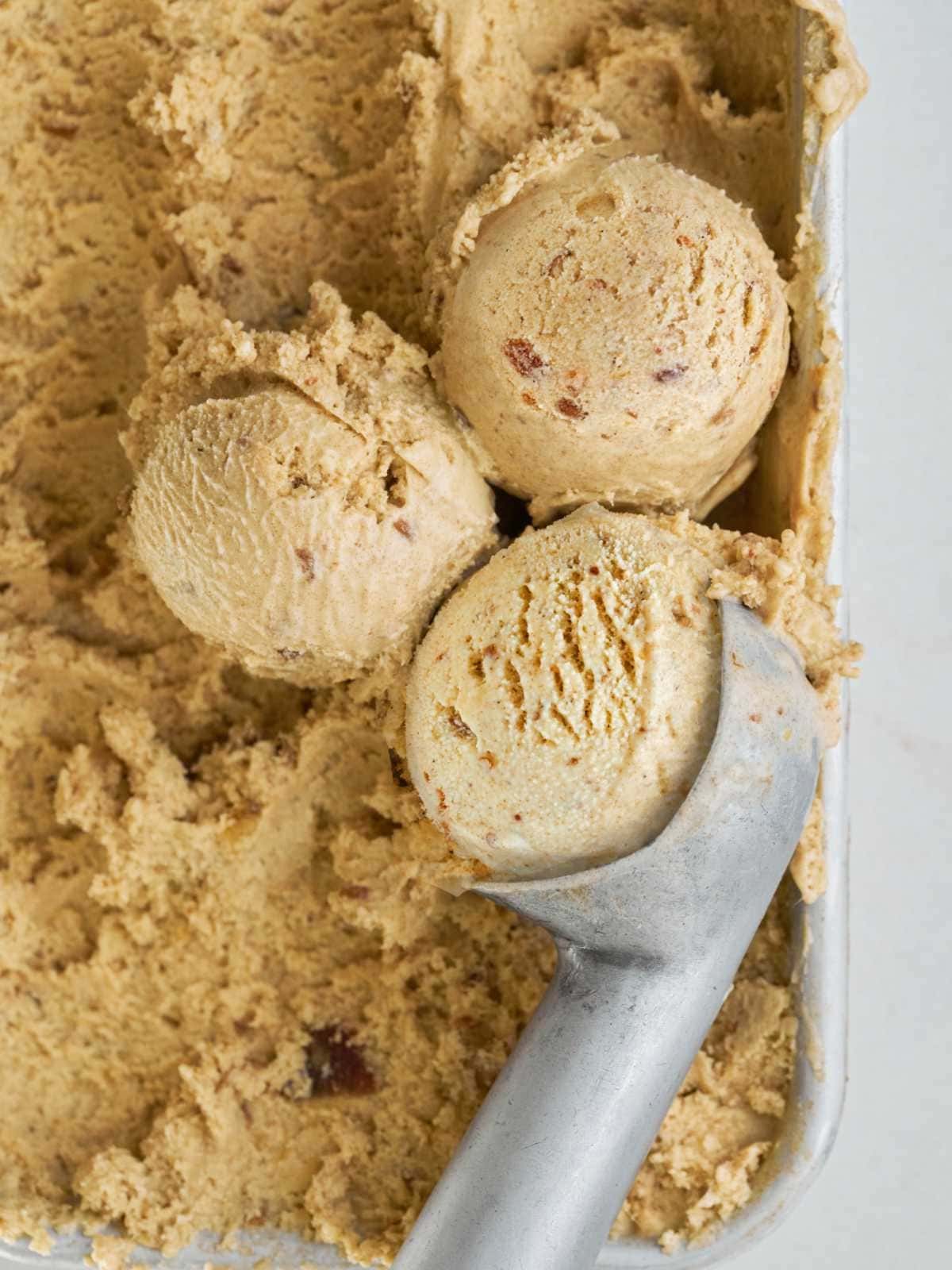 Vanilla date ice cream in a pan with scooper.