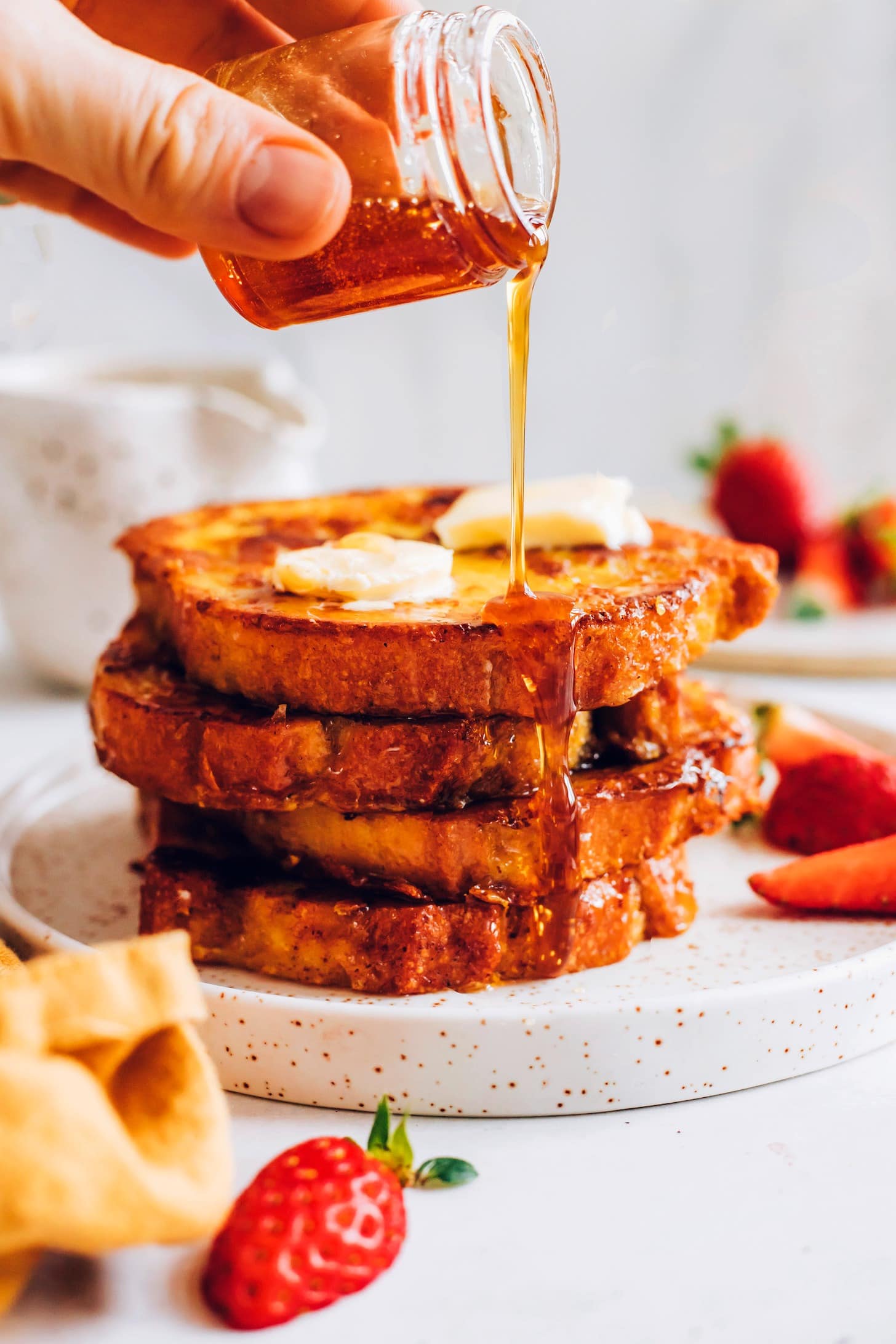 Stack of French toast poured with maple syrup.